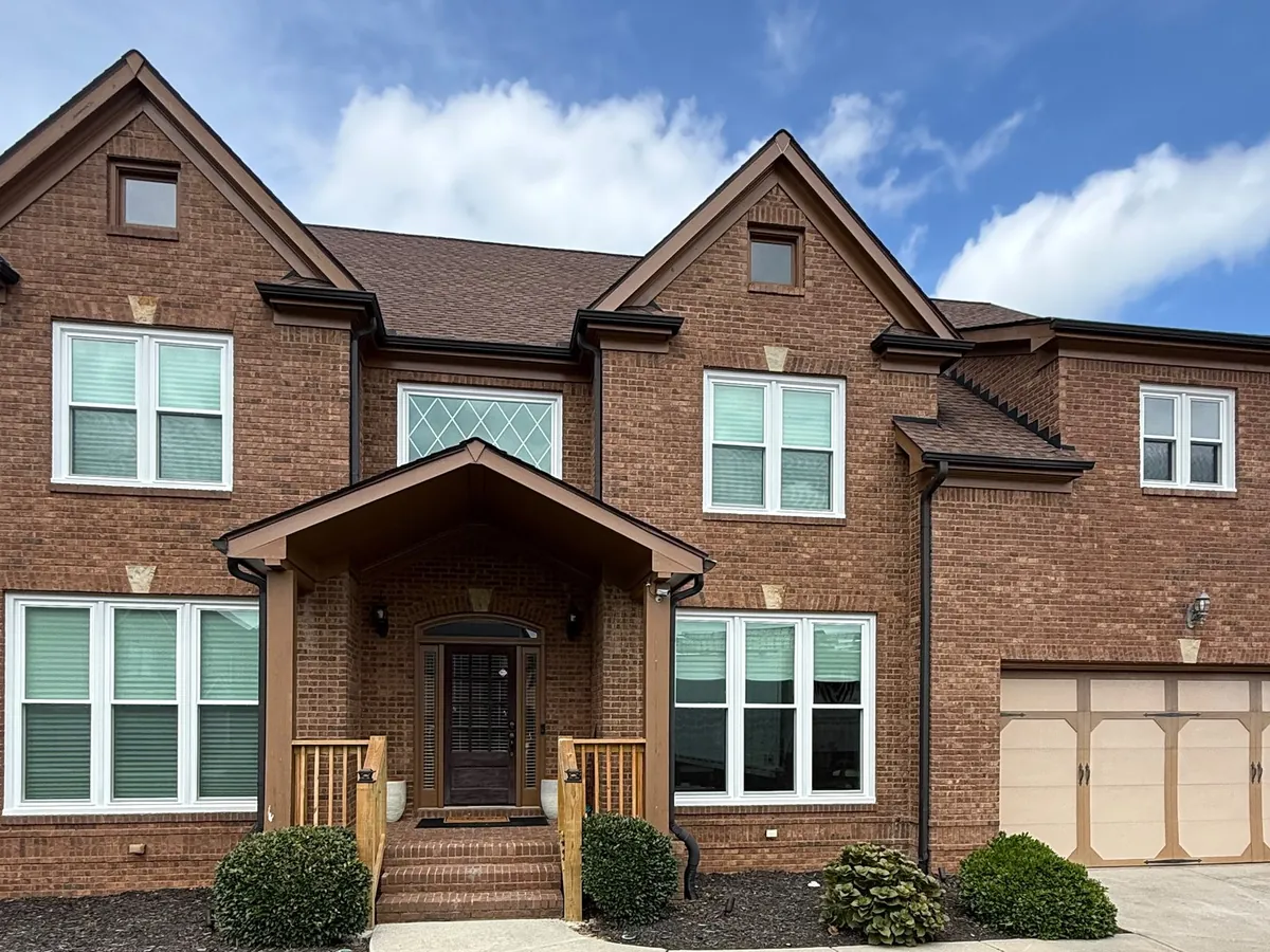 White windows on a brick two-story with a diamond-grid accent window