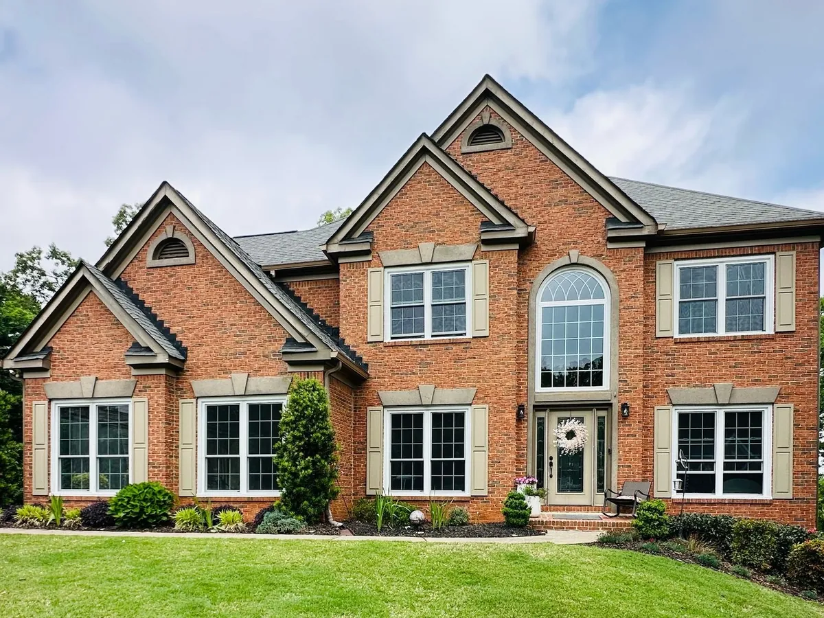 Double hung windows with grids and an arched window over the front door