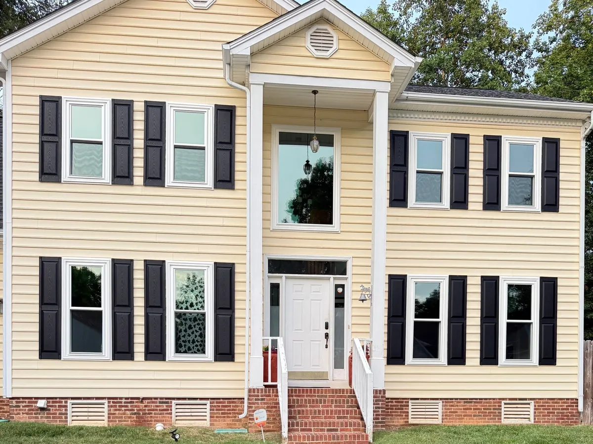 Double hung windows with black shutters on a two-story siding home